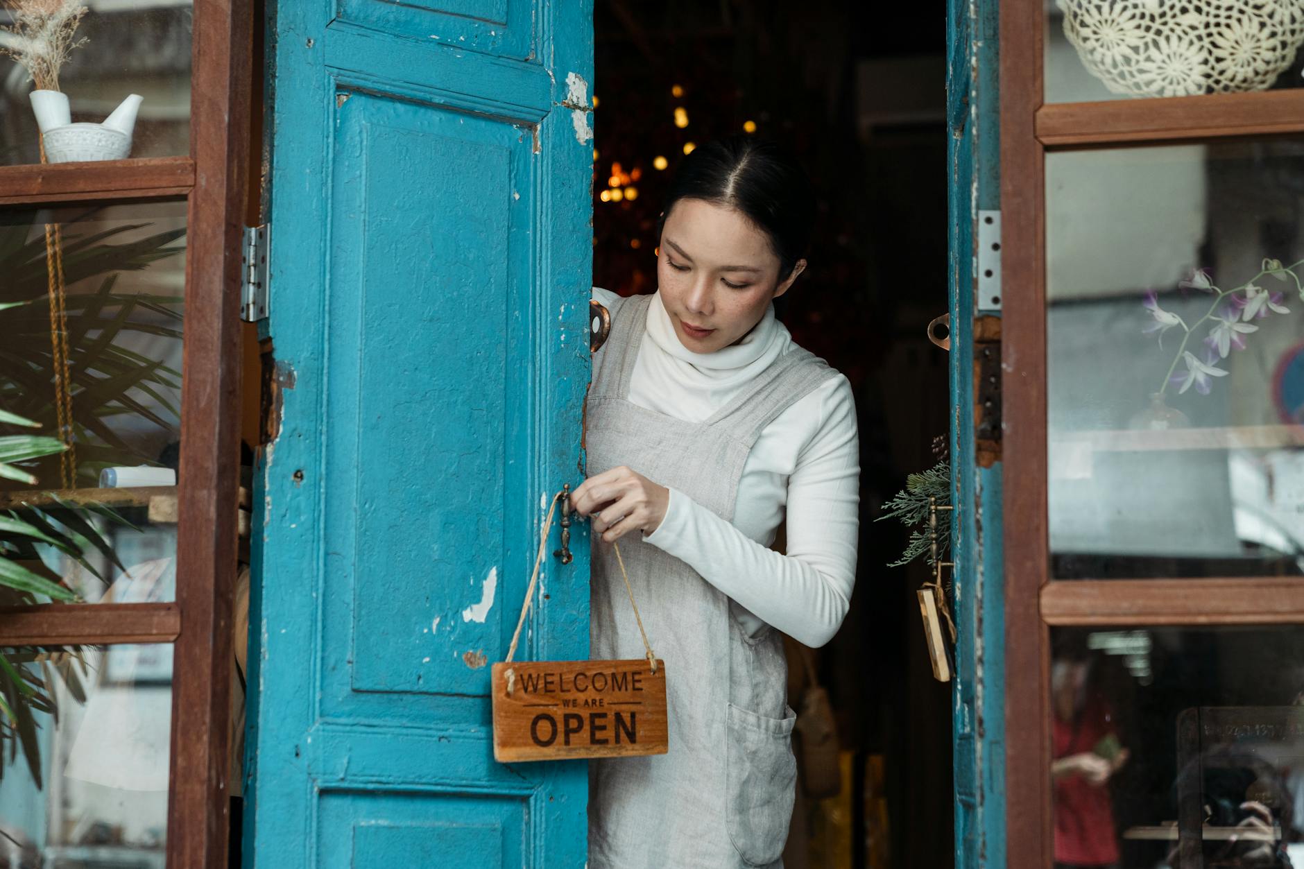 photo of woman putting wooden signage on doorknob